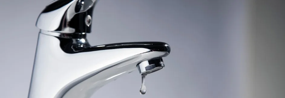 Chrom Wasserhahn, aus dem ein Tropfen Wasser fällt